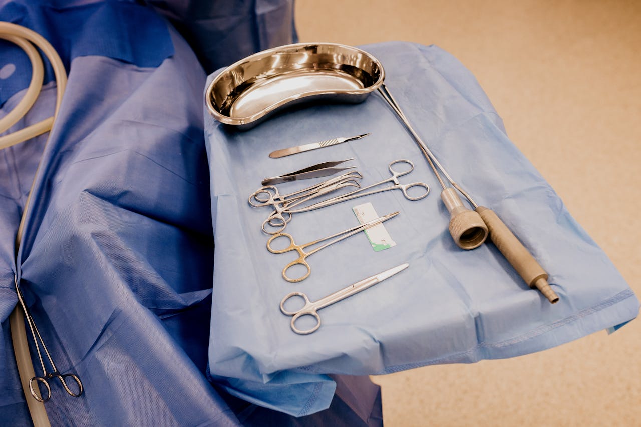 A set of surgical instruments arranged on a blue drape in a sterile operating room setting.