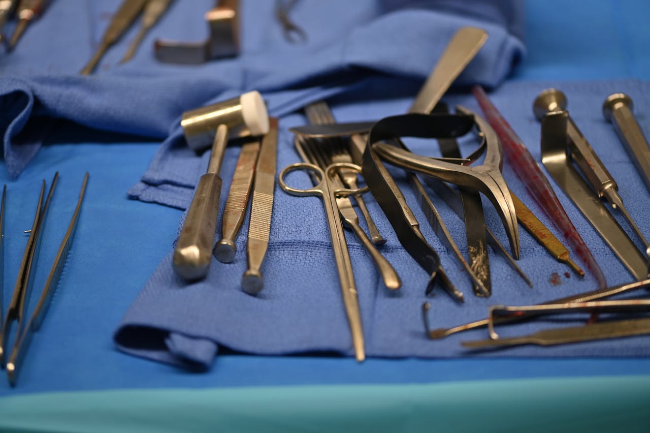 Close-up of various surgical tools laid out on a blue cloth in a medical setting.