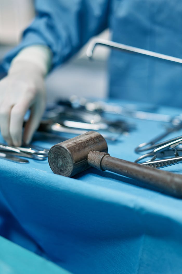 A detailed view of surgical tools and a surgeon's hand in an operating room setting.